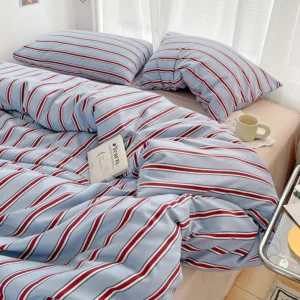 Schlichter rot-blau gestreifter Bettbezug und vierteiliges Bettlaken-Set mit Bettwäsche aus gewaschener Baumwolle auf dem Bett